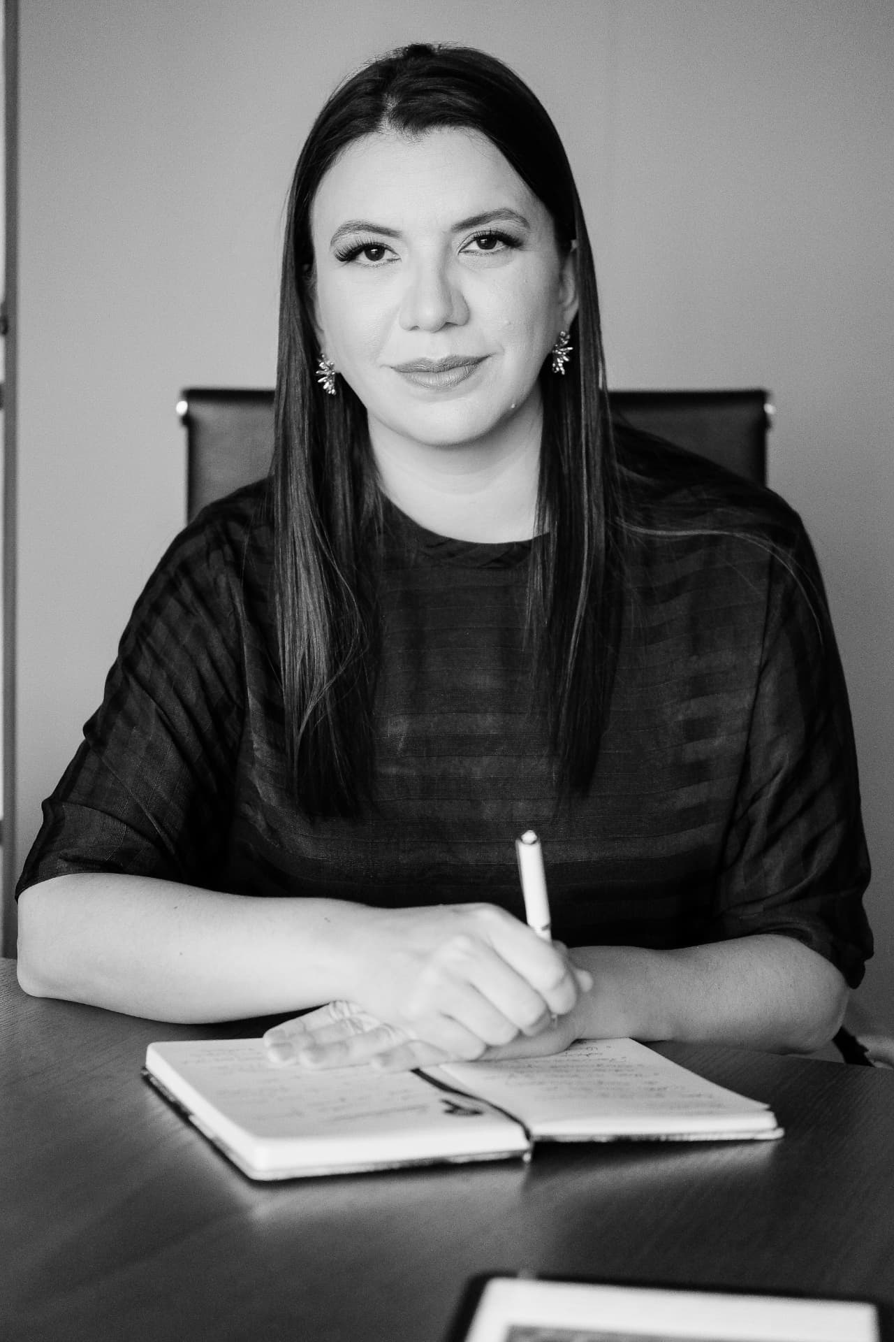 Dra. Tarsila Maia, médica intensivista, sentada à mesa com um caderno aberto